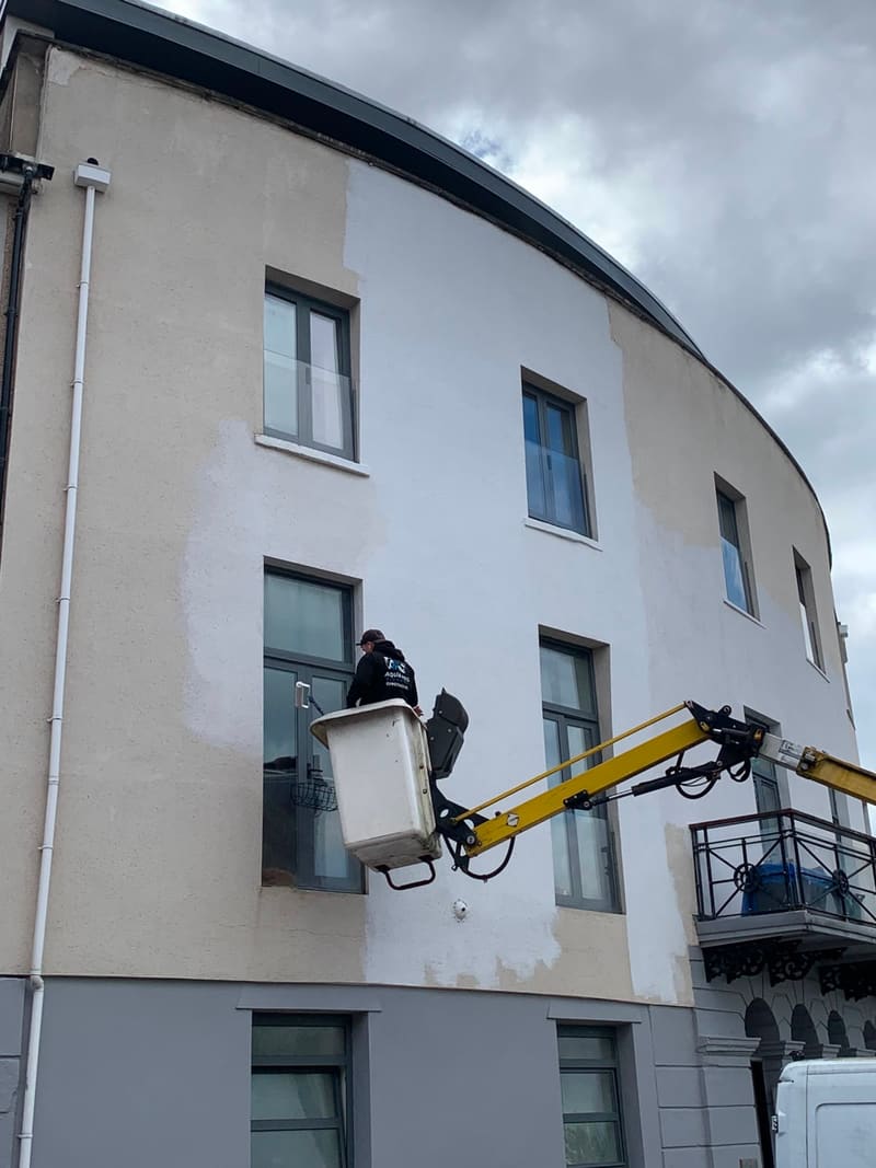 Worker in a cherry picker painting a building exterior