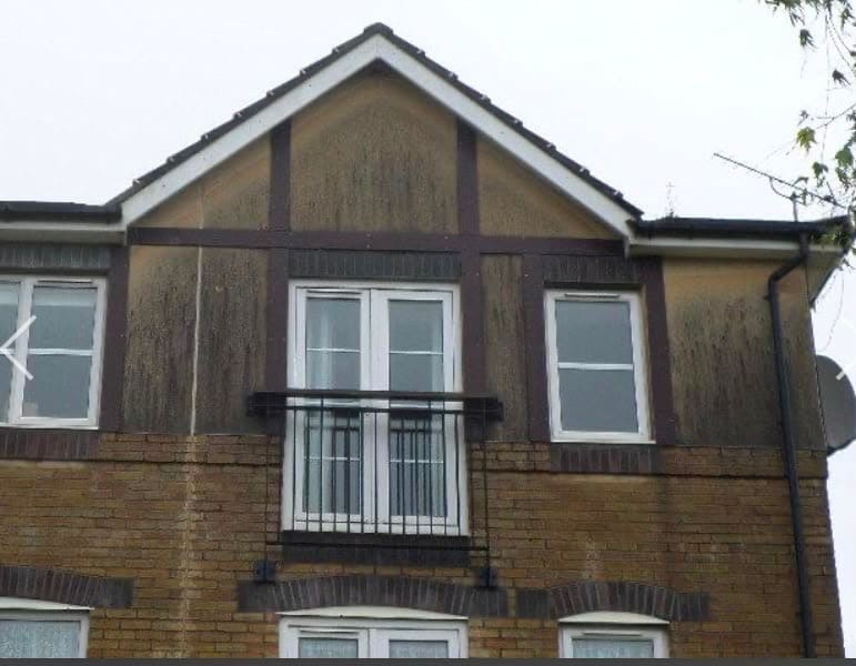Discoloured render and brickwork on a house exterior before cleaning
